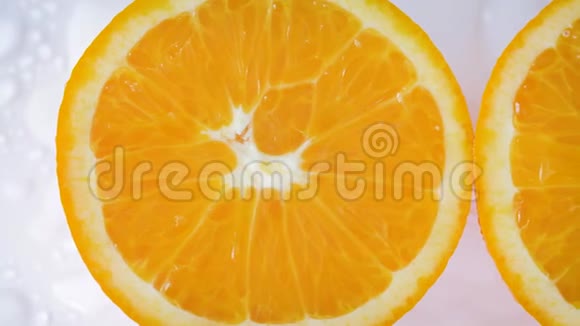 在白色和潮湿的背景上沿着橘子切片滑动视频的预览图