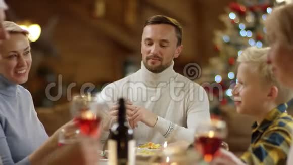 幸福的家庭成员在圣诞节的餐桌旁碰杯喝酒视频的预览图