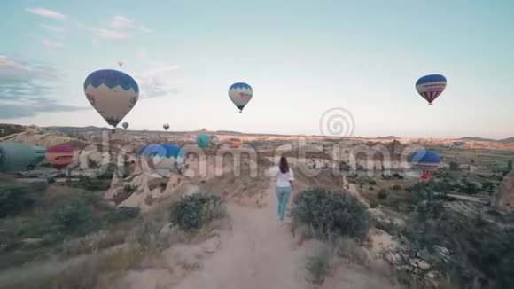 美丽的年轻女子日出时带着热气球走来走去稳定镜头视频的预览图