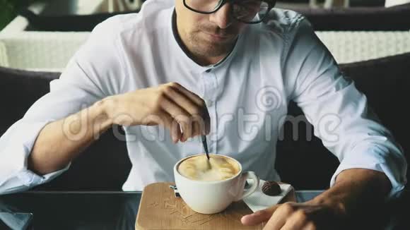 年轻的商人穿着商务服装和眼镜坐在咖啡馆里视频的预览图