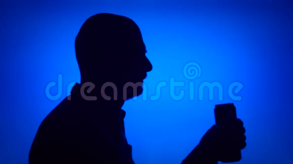 老人打开蓝色背景啤酒罐的剪影喝苏打水的男人脸视频的预览图