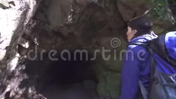 带着背包和手电筒的旅游女孩进入一个黑暗的洞穴看着石头蒸汽来了视频的预览图