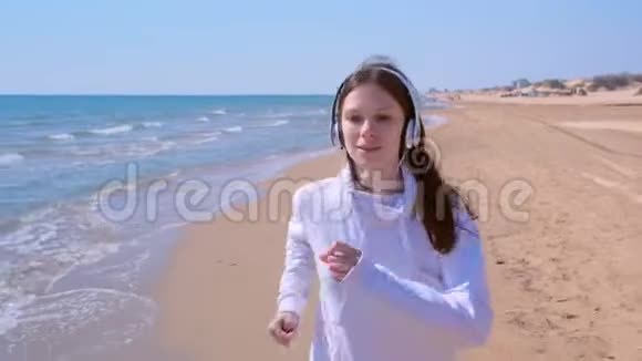 女士戴耳机音乐慢跑在海沙滩运动跑步户外训练视频的预览图