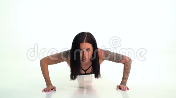 漂亮的黑发女人有纹身做俯卧撑动作慢视频的预览图
