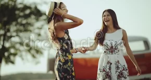 两个上镜的年轻女子穿着复古时尚的连衣裙在大自然的中间微笑着拥抱着对方视频的预览图
