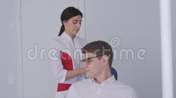 一位女牙医站在椅子旁边为病人准备口腔检查视频的预览图