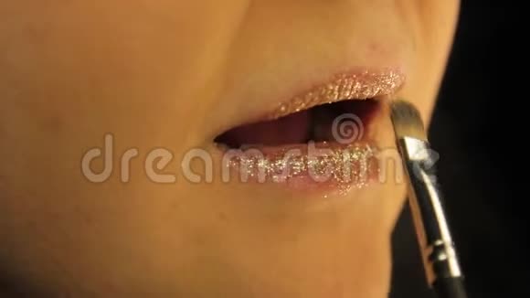 一只女性的手用金光闪闪的唇妆视频的预览图