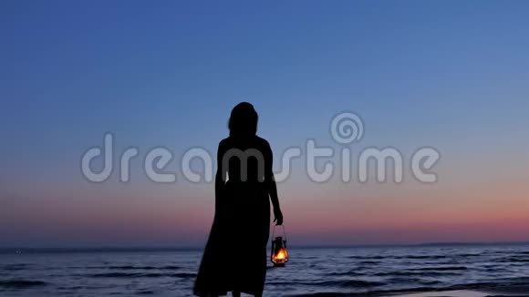 孤独的女性穿着煤油灯看着夕阳的夜空视频的预览图