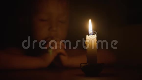小可爱的小女孩正在祈祷前面燃烧蜡烛特写视频的预览图