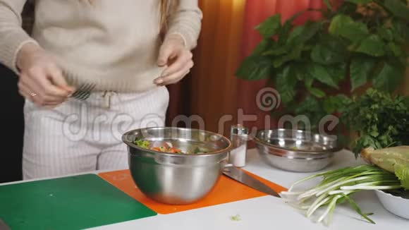 女人把蔬菜沙拉拌在碗餐具里混合素食沙拉的成分蔬菜沙拉的准备视频的预览图