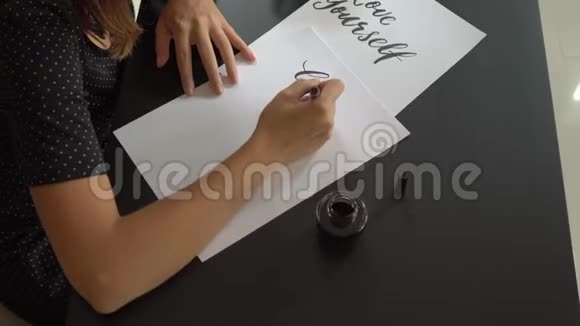 一位年轻女子用刻字技巧在纸上书写书法的特写镜头她写的是爱自己视频的预览图