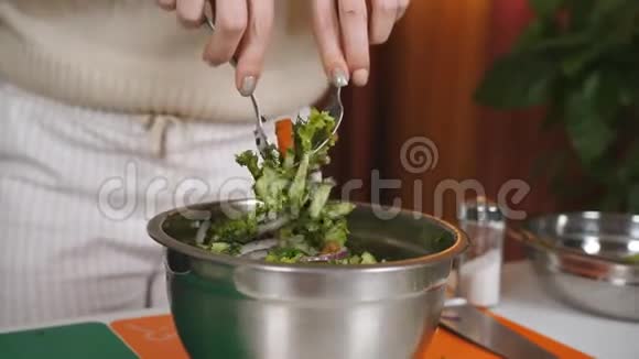 女人把蔬菜沙拉的原料混合在碗里在碗中加入搅拌蔬菜沙拉混合视频的预览图