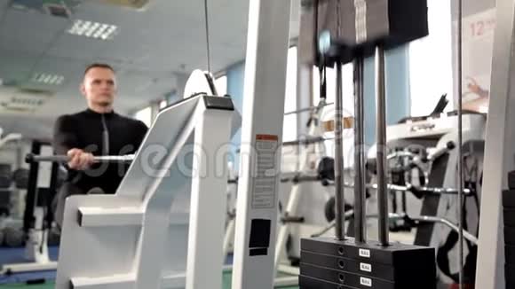 背部的肌肉男人在健身房的赛艇机上训练一个男人在健身房里举重这就是视频的预览图