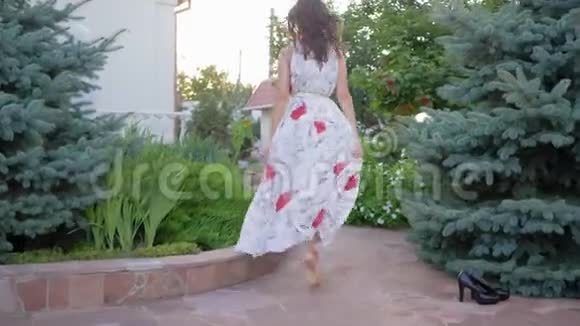 女人的魅力光着脚穿着长裙的女人在花丛中招手沿着小路奔跑视频的预览图