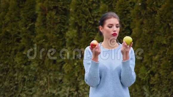 一位漂亮的年轻女子穿着蓝色夹克选择了绿苹果和红苹果视频的预览图