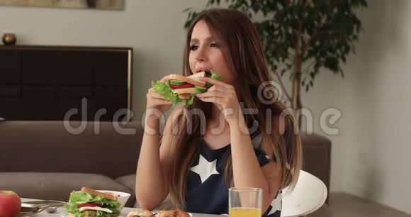 可爱的饥饿的女人吃着美味的三明治享受食物视频的预览图
