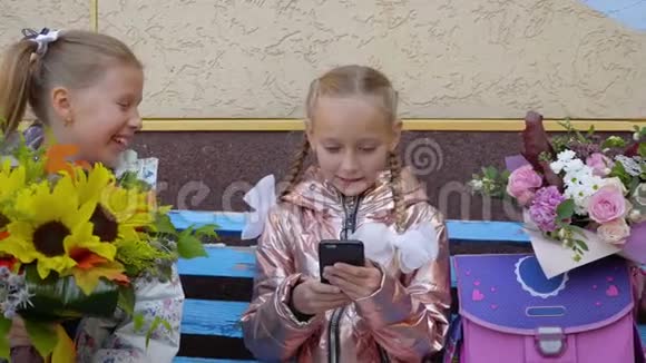 两个带电话和花束的快乐女学生坐在长凳上视频的预览图