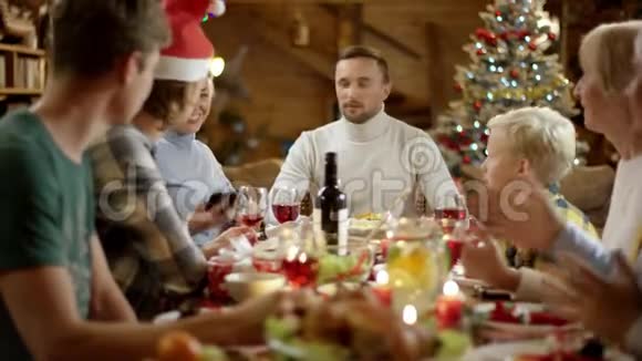 妈妈在圣诞晚餐上和家人一起在智能手机上集体自拍视频的预览图