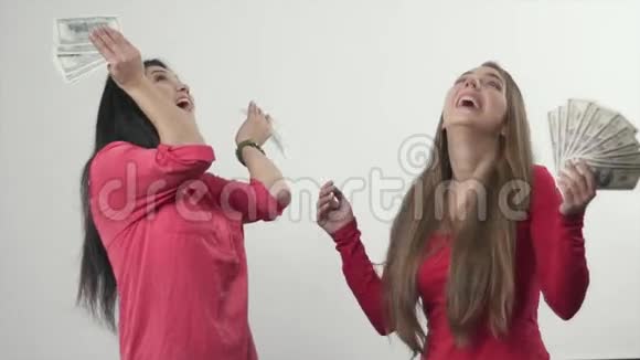 两个女孩站在雨中从天上掉下来的钱慢动作视频的预览图