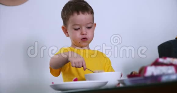 小可爱的孩子在桌子上吃自己的燕麦片和燕麦Exotic水果婴儿吃的意愿概念视频的预览图