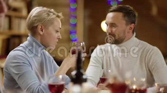 快乐的情侣们在圣诞夜的餐桌旁喝酒视频的预览图