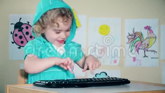 顽皮可爱的小女孩玩电脑键盘看相机视频的预览图