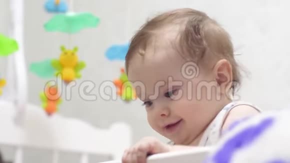 小孩子站在婴儿床上可爱的宝贝笑了视频的预览图