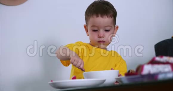 小可爱的孩子在桌子上吃自己的燕麦片和燕麦Exotic水果婴儿吃的意愿概念视频的预览图