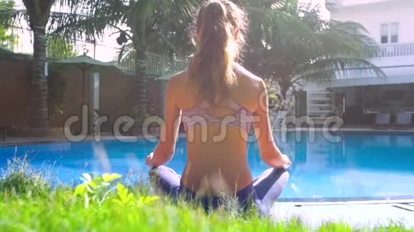 金发女孩放松在瑜伽姿势莲花池的背面视图视频的预览图