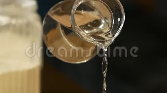 从玻璃罐中倒入面粉中的水用于厨房准备面团视频的预览图