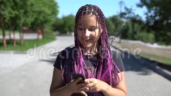 一个长辫子的漂亮女孩用手机在公园里散步视频的预览图