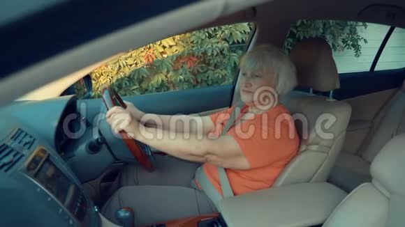 听音乐的高级妇女在车里拿着方向盘视频的预览图