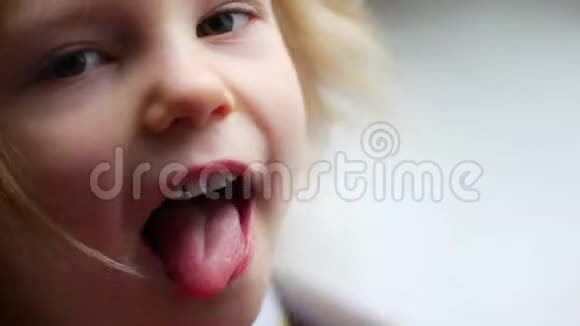 小女孩脸上的肖像鬼脸舌头镜头视频的预览图