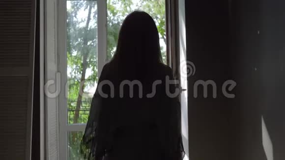 早上穿丝绸长袍的年轻女子在阳台上享受新鲜空气视频的预览图