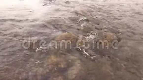 河流中棕色石头上的水流细节灰色阴天视频的预览图