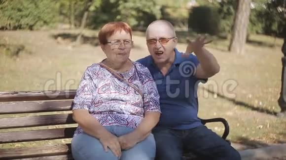 快乐的退休夫妇在公园里互相享受公司的约会公园长椅上的一对老夫妇视频的预览图