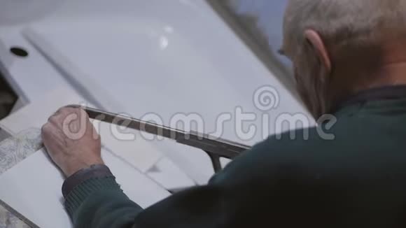一位老人用手锯锯一根塑料棒视频的预览图