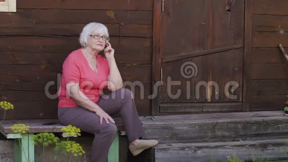 坐在乡间木屋旁的长凳上打电话视频的预览图