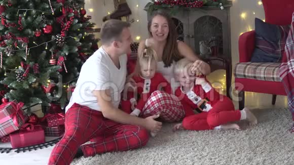 一家人正坐在那棵打扮得漂漂亮亮的圣诞树旁视频的预览图