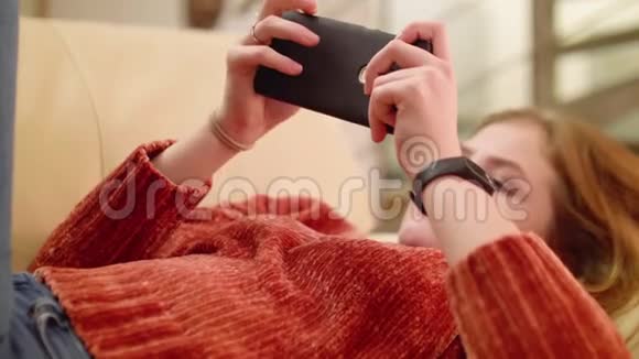 女孩躺在沙发上在智能手机上上网视频的预览图