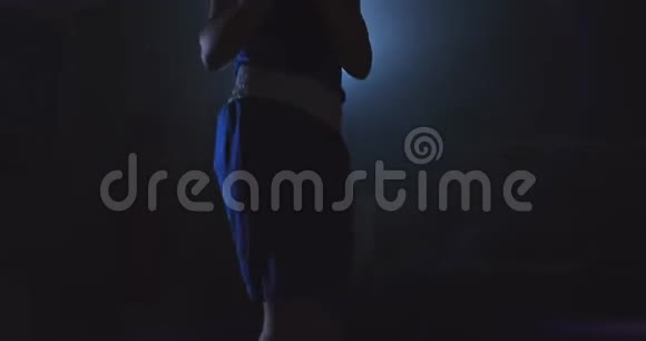 年轻漂亮的女子在大厅里训练职业拳击手在黑暗中在对冲的光线下跳上一根绳子视频的预览图