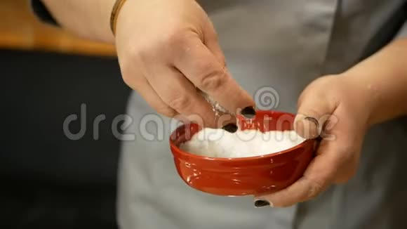 女人的手把海盐撒在锅里的生面团上烹饪过程视频的预览图