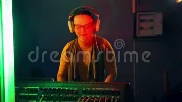 一位带耳机的女DJ在一个技术室的灯光下在一个混合控制台进行迪斯科视频的预览图