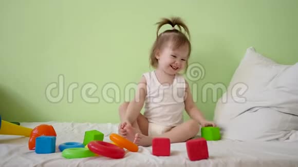 孩子在一张白色的床上玩五颜六色的立方体然后把它们扔给他的母亲学前教育和教育玩具视频的预览图