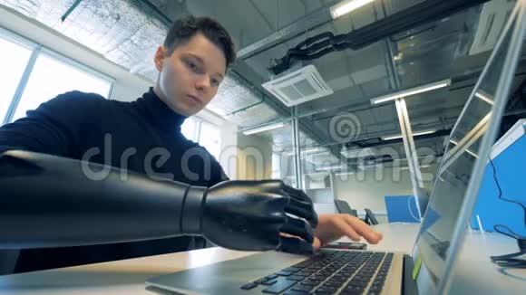 人类在笔记本电脑上打字的假肢机器人机械臂概念视频的预览图