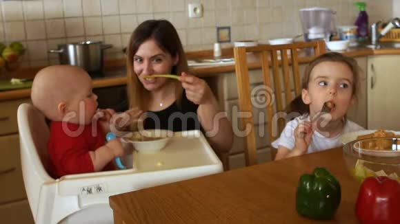 母亲喂坐在高椅上的婴儿孩子不想吃东西用手抓着勺子母亲视频的预览图