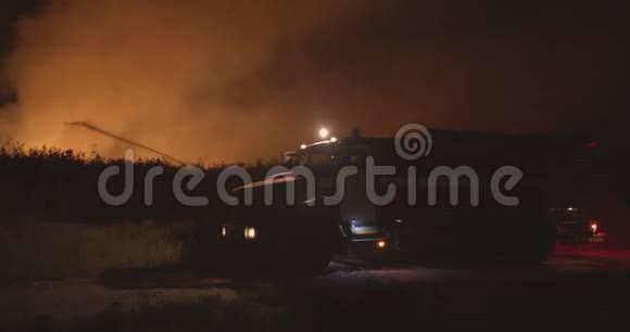 开着闪烁灯的消防车森林火灾时在野外焚烧草地背景下的消防车救援和救援视频的预览图