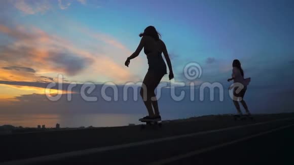 女孩的剪影在滑板上骑在路上岩石和天空美丽的日落相机在里面视频的预览图