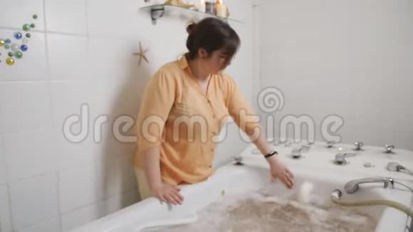 一个男人坐在医用浴油里一个在水疗中心的女员工从热水中得到按摩一种特殊的技术一种视频的预览图