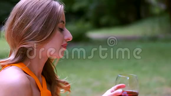 公园里金发女孩喝酒的特写镜头视频的预览图